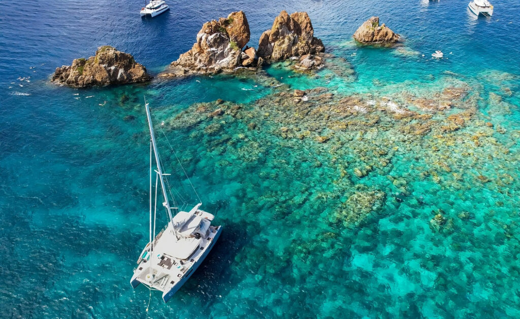 Fantastic shot of the catamaran Liquid Zen moored at the Indians off Norman Island, BVI. Located just off the southwestern tip of Norman Island in the British Virgin Islands, 'The Indians' are deemed one of BVI's best shallow dive sites. Descending about fifty feet beneath the surface, these rocky pinnacles unveil a mesmerizing underwater world with abundant coral gardens teeming with colourful fish. You can also find a 15-foot underwater tunnel!