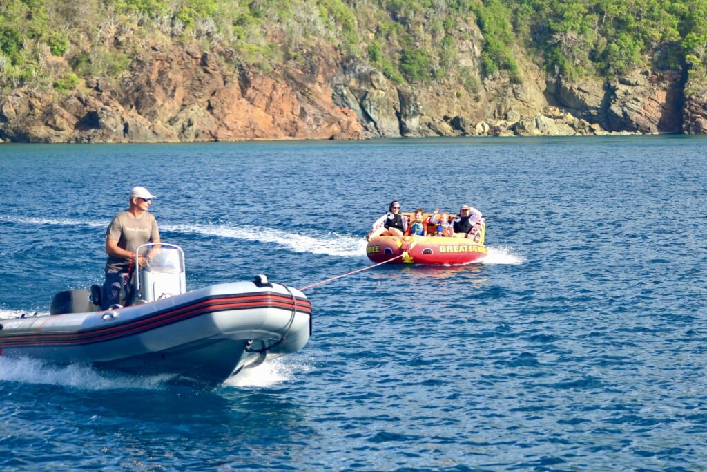 Kids on the tube behind the tender of crewed catamaran TRANQUILITY in the BVI