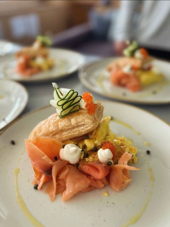 Amber's Smoked salmon, creamy scrambled eggs, and puff pastry, garnished with delicate cucumber ribbons, dollops of cream cheese, capers, and salmon roe. Finished with a drizzle of olive oil.