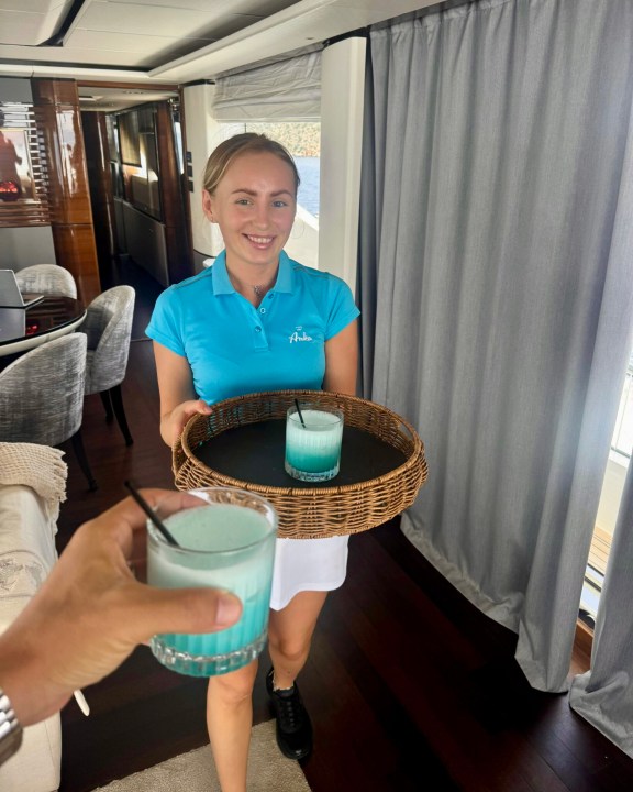 Stewardess serving cocktails onboard luxury motor yacht ANKA